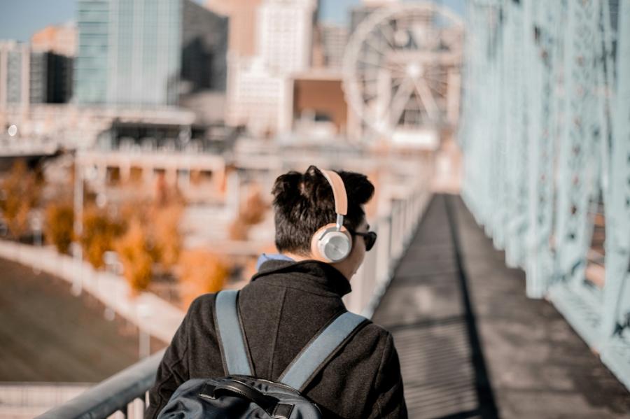 Person wearing pink headphones, walking outdoors in a city