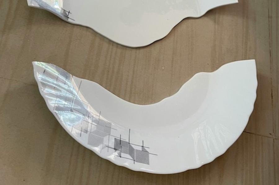 White plate, broken in half on a wood floor