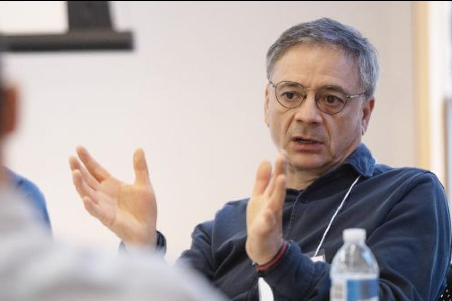 Older man with glasses and gray hair talking with his hands.
