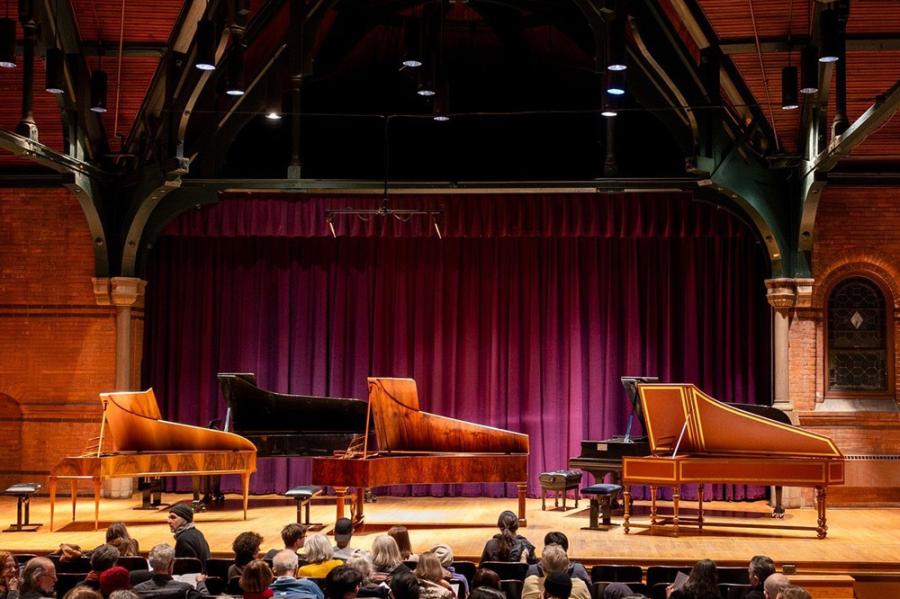 Stage with five pianos on it