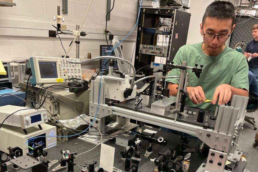 Man with glasses and t-shirt working on complex electronic table-top machine