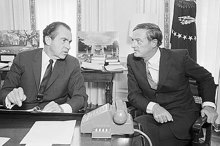 Historic photo of two men in suits at a desk, conferring: Richard Nixon and William F. Buckley