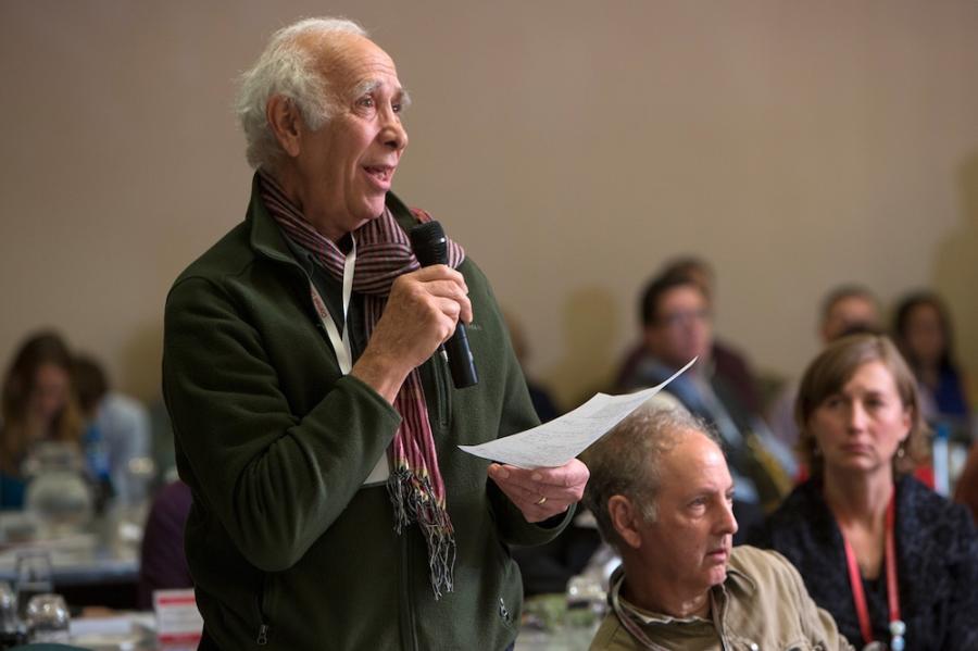 Person holding a piece of paper and speaking into a microphone