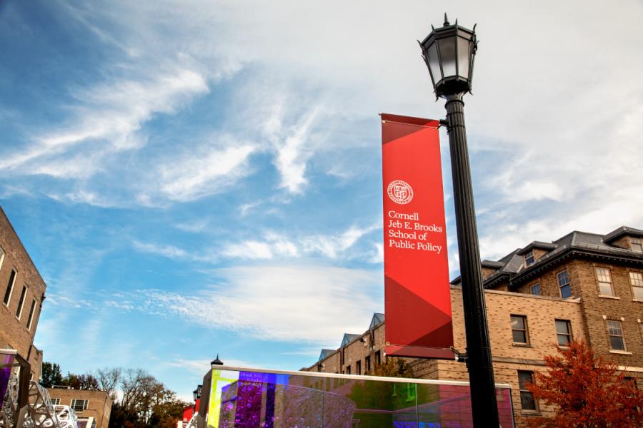 Lamp post with a red banner attached: Cornell Jeb E. Brooks School of Public Policy