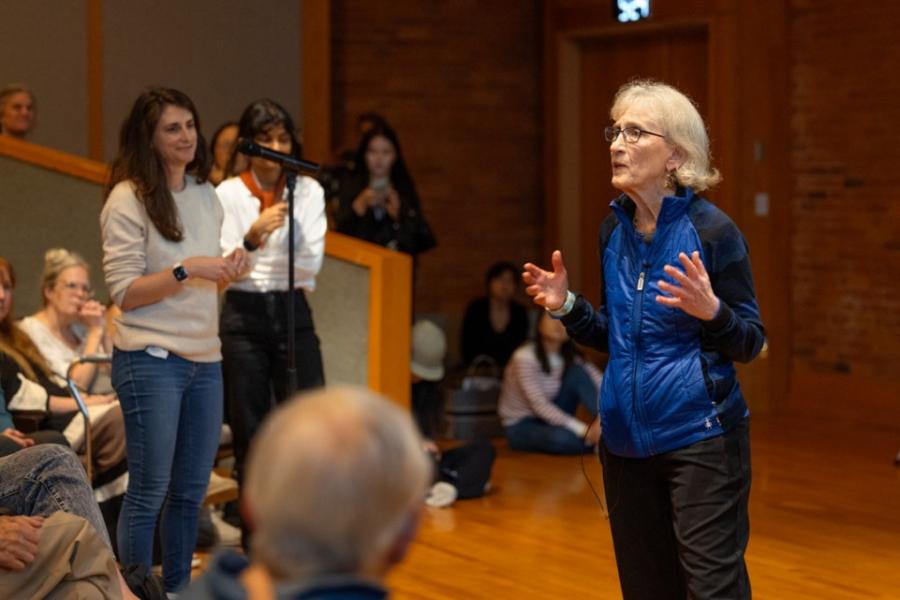 Person speaking in front of an audience in a packed auditorium
