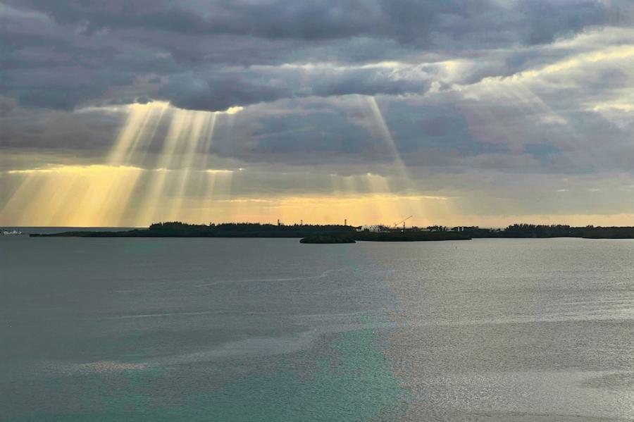 Sun beams shoot through heavy clouds over a bay