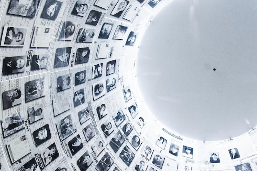 hundreds of black and white portrait photos on a wall leading up to a light grey dome