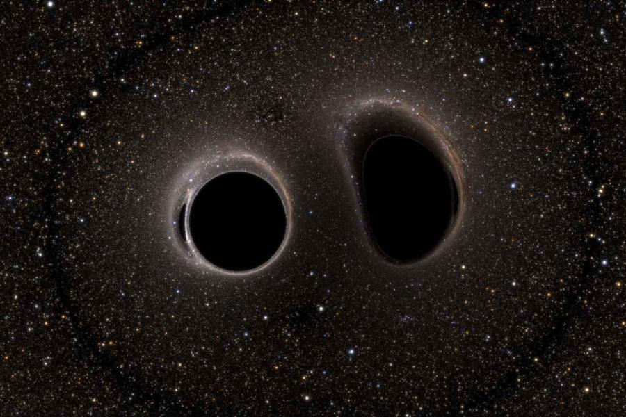 A field of stars surrounding one circular and one oblong area of extreme blackness surrounded by a halo of light