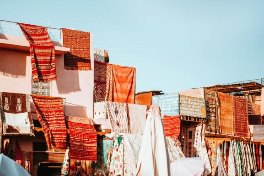 Colored rugs make a collage under a blue sky