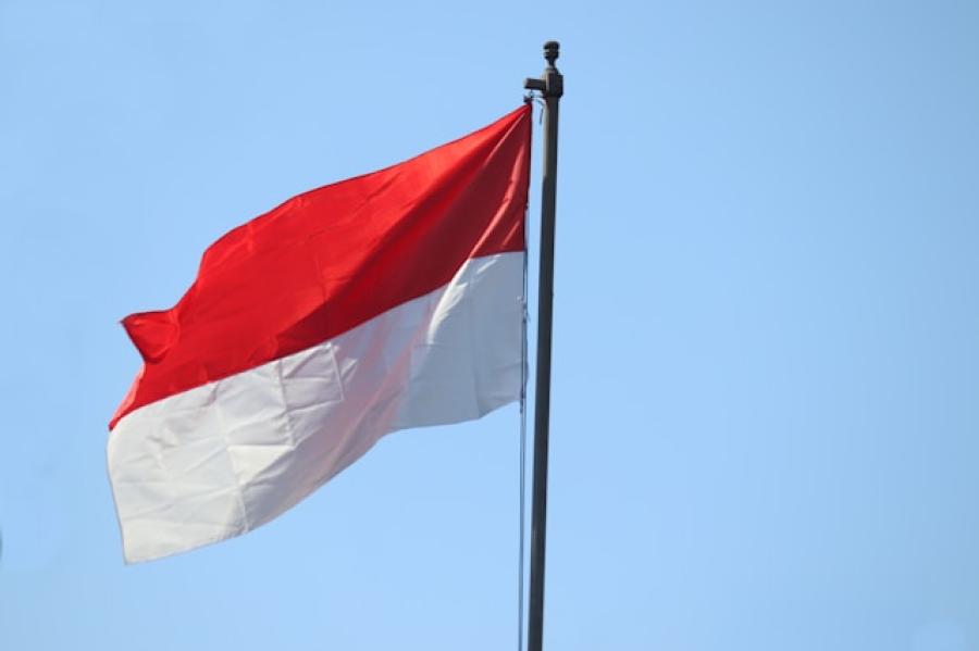Flag with broad red stripe on top and broad white tripe on bottom on flagpole against a blue sky.