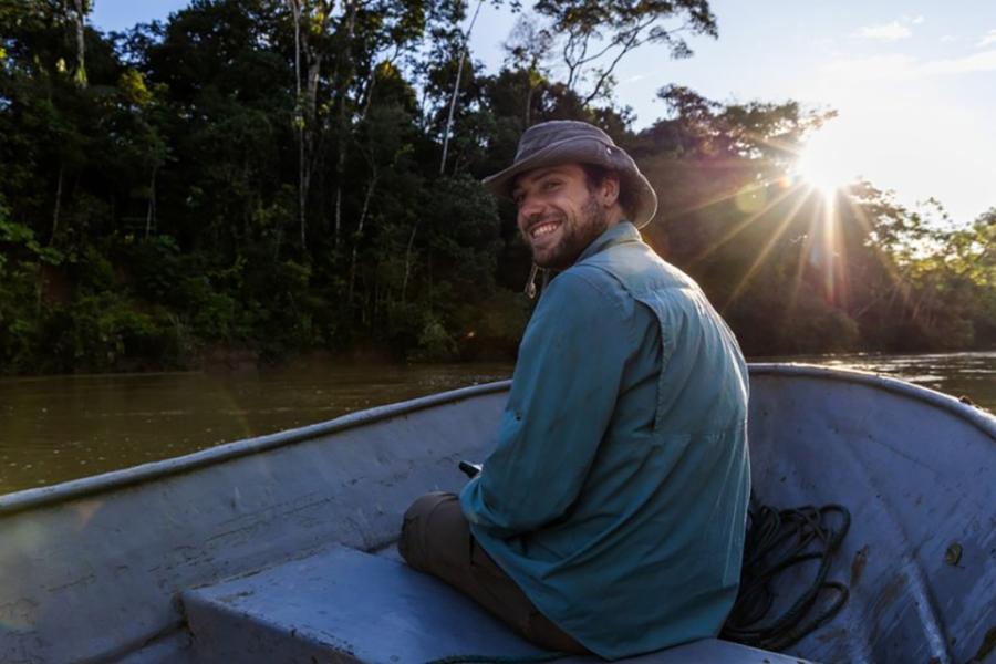 Person in a small boat on a river, turning around and smiling