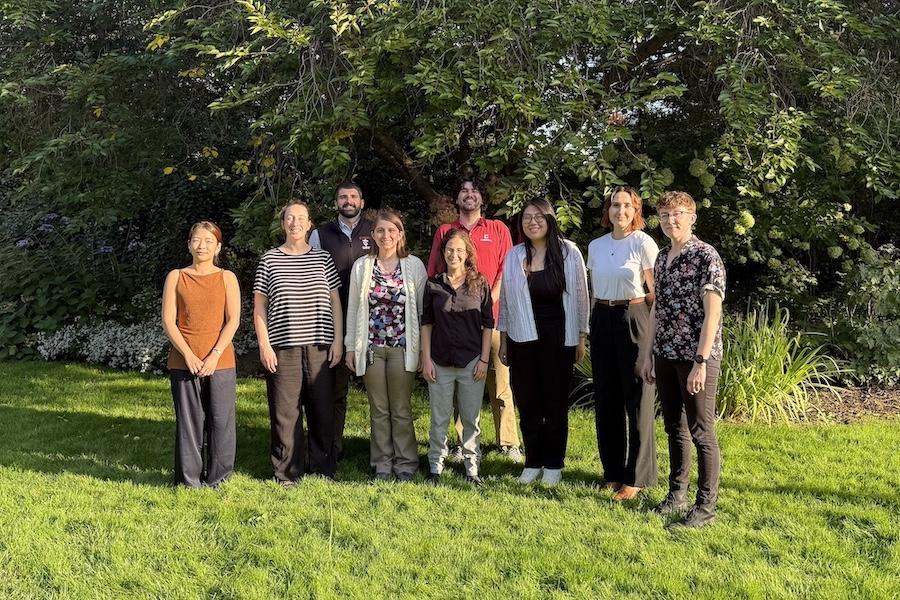 Nine people standing in a grassy area