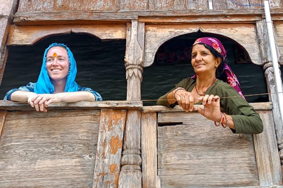 Two people leading out of windows in a wooden building