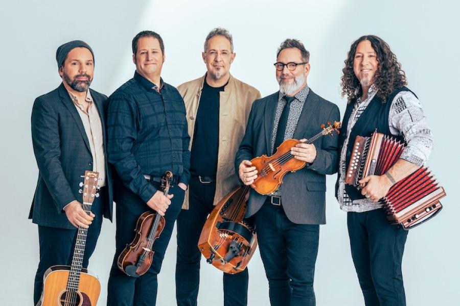 Five musicians hold folk instruments in a publicity portrait