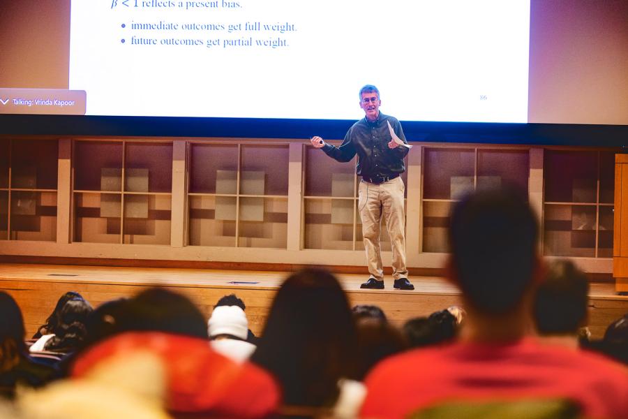 Professor Ted O’Donoghue lectures on in front of a full class of students.