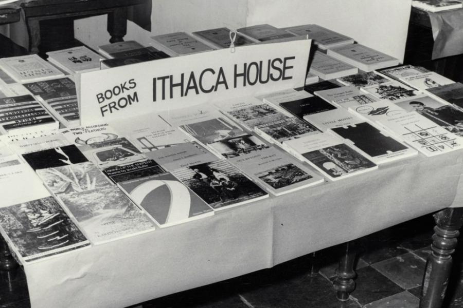 Black and white photo of a tale covered with books for sale from "Ithaca House" press