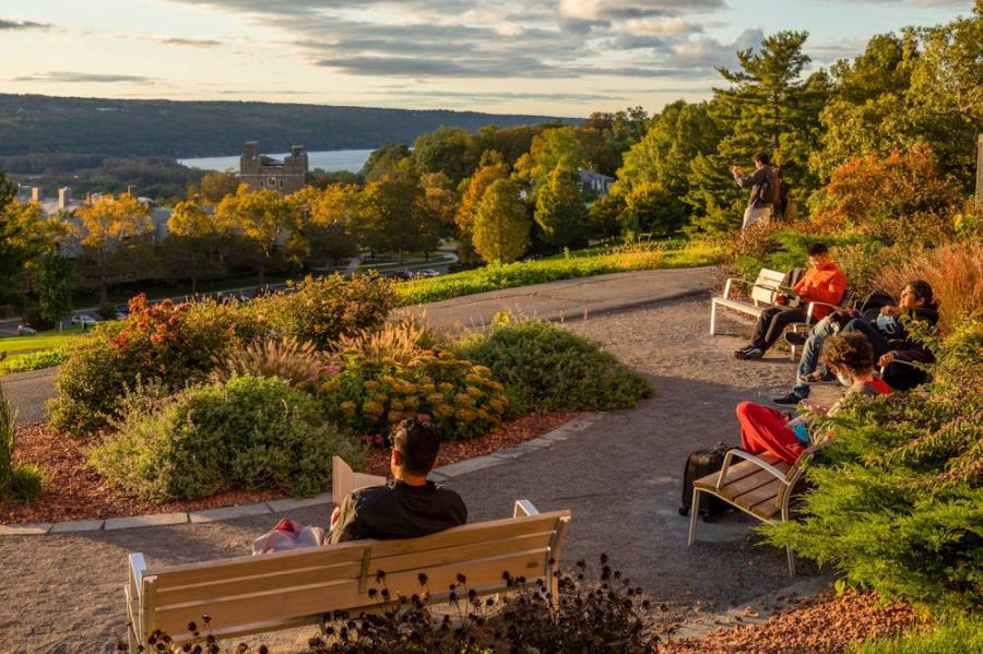 People reading on benches that overlook a grand view of a lake and autumnal trees