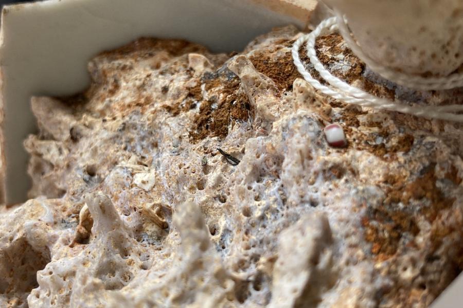 Lumpy, tawny, textured surface with one smooth bead embedded in it