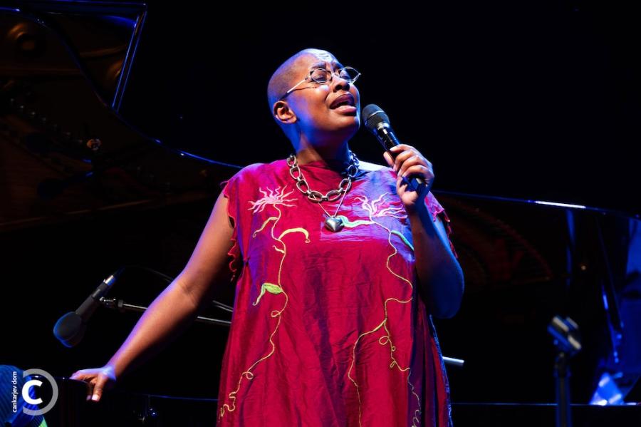Person in a red dress, singing into a microphone