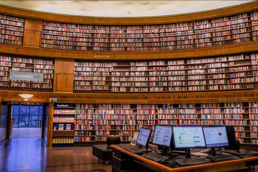 books in a library with computers on table