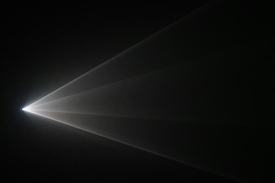 Light source sends white rays across a dark space