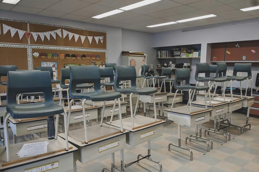 A classroom empty of students; the chairs are on desks