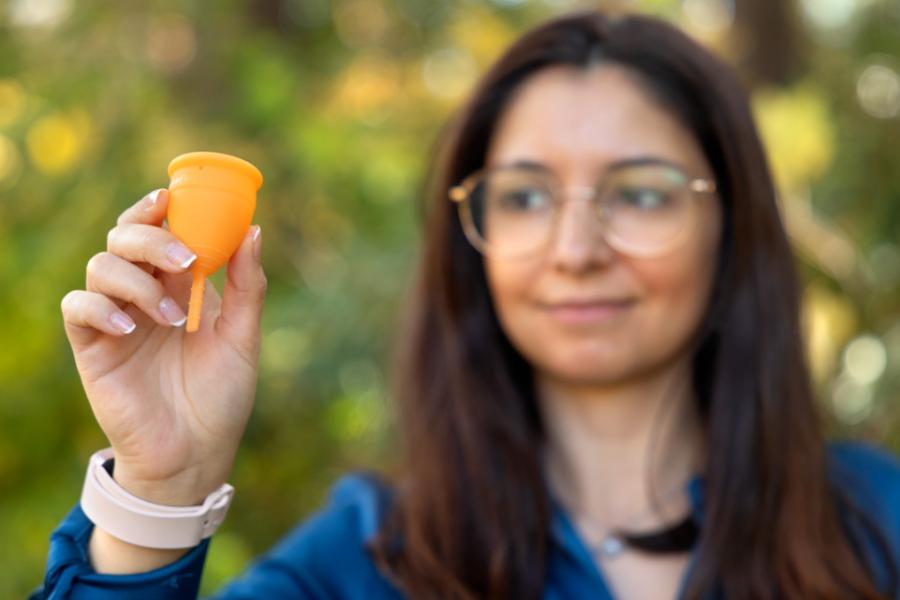 Person holding up an orange menstrual cup