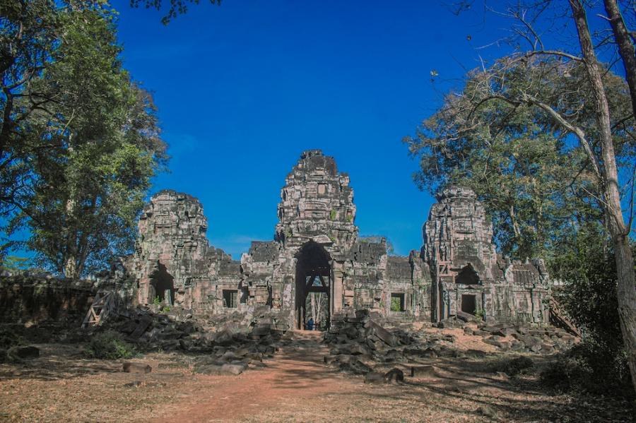 ancient stone temple surrounded by trees, under a bright blue sky