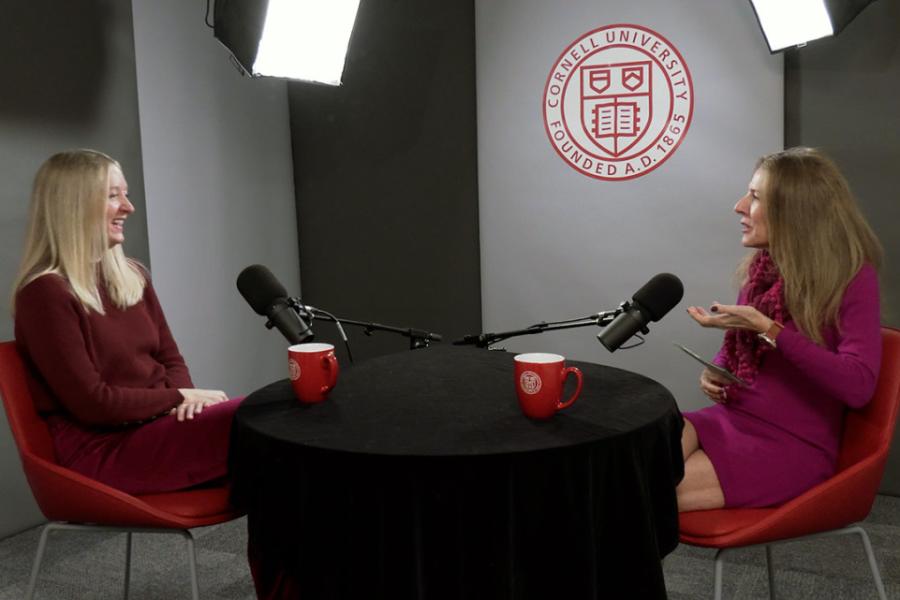 Two people conversing at a black round table, talking into microphones