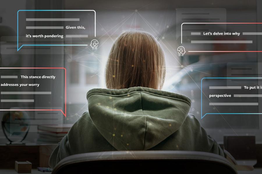 Seen from the back a person wearing large hooded sweatshirt faces a computer screen