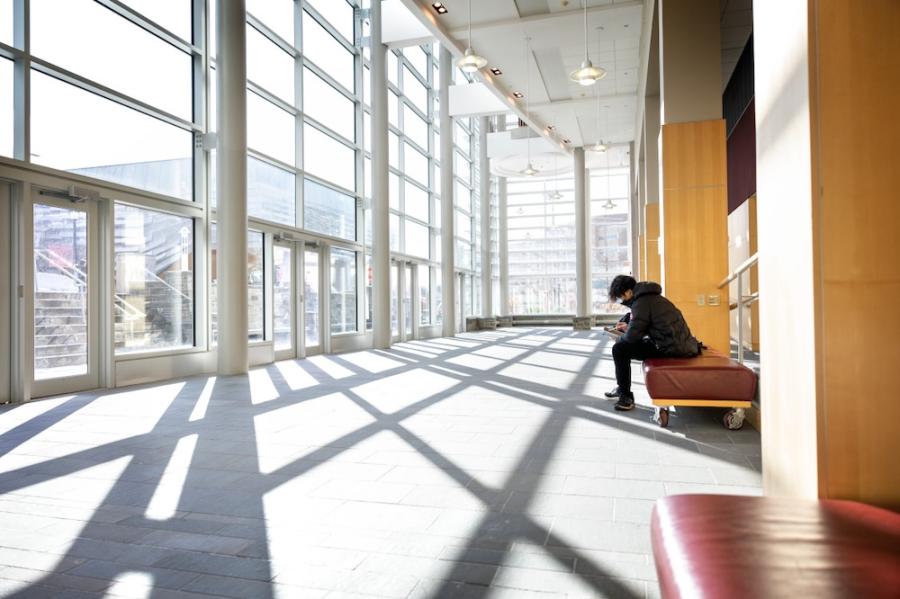 person reading on a bench in a large, sunny, modern room