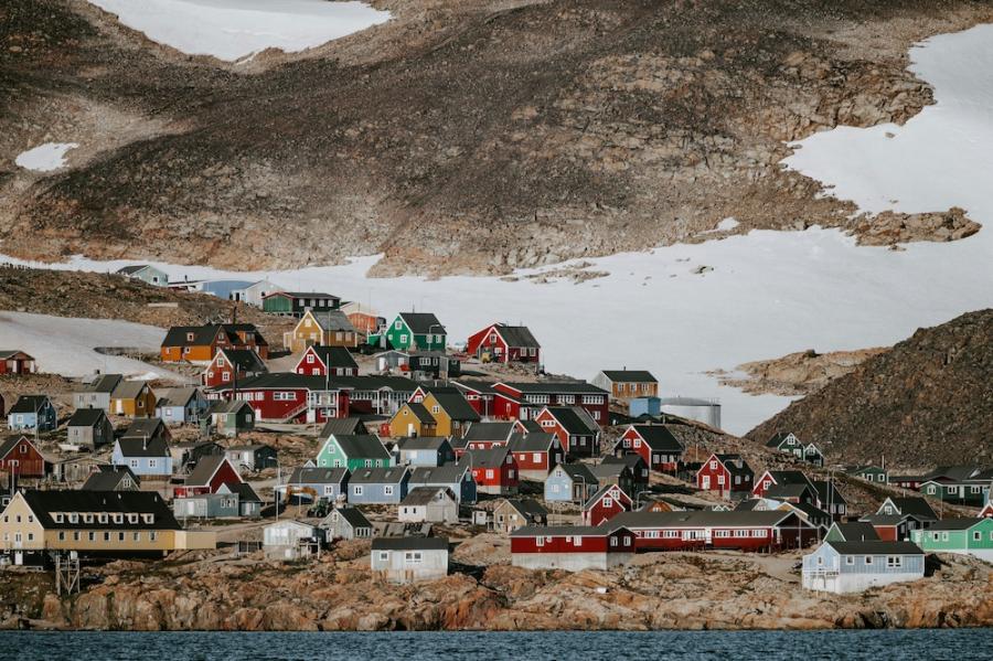 Hill with dozens of colorful houses on it, backed by a bleak landscape with snow