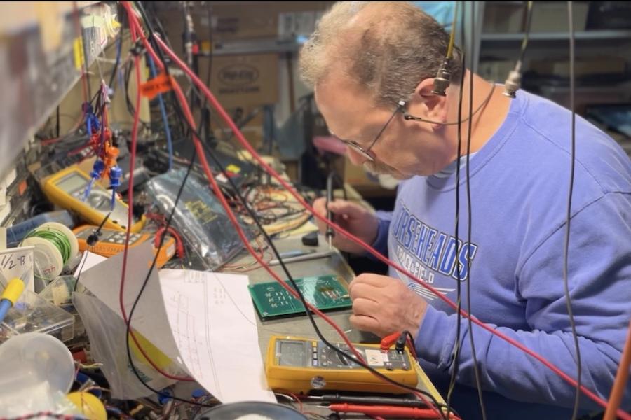 Person seated at a work bench, working on small electronics
