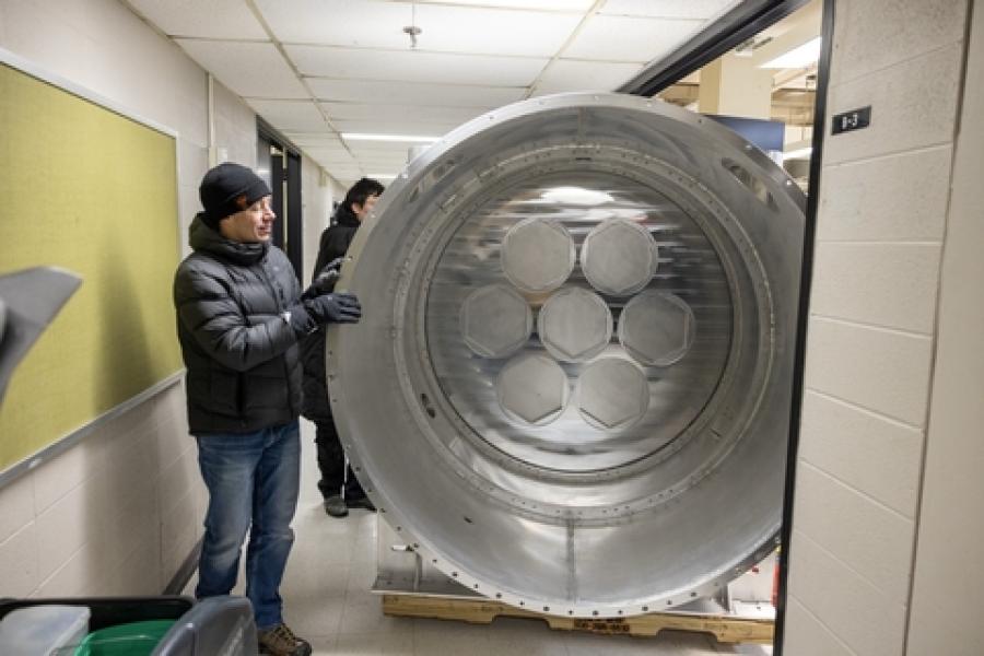 Person in a hallway next to a circular piece of equipment that takes up most of the hallway