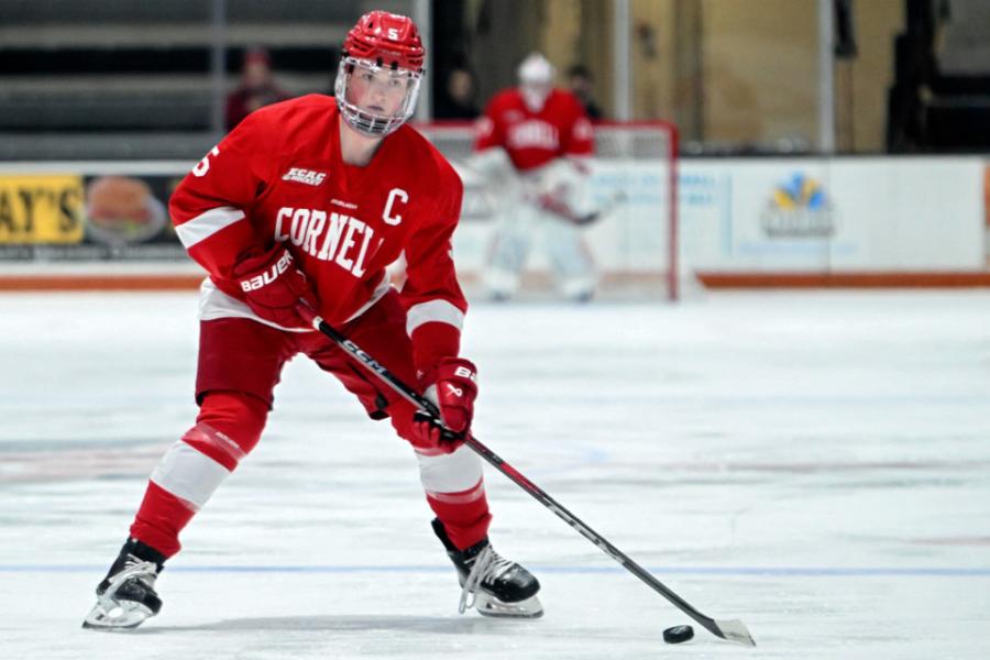 Person in red hockey gear, puck near the stick
