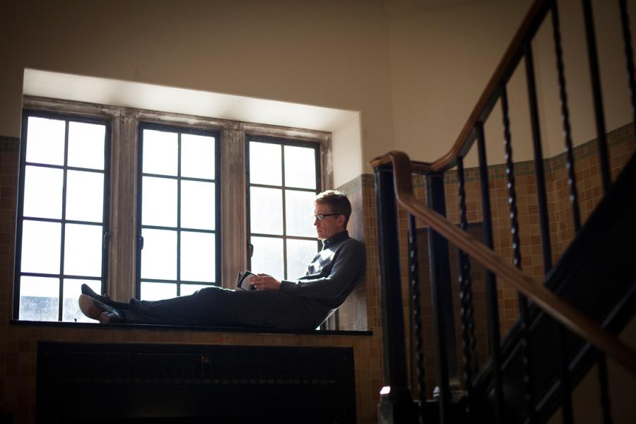 Person sitting in a deep windowsill, reading a book