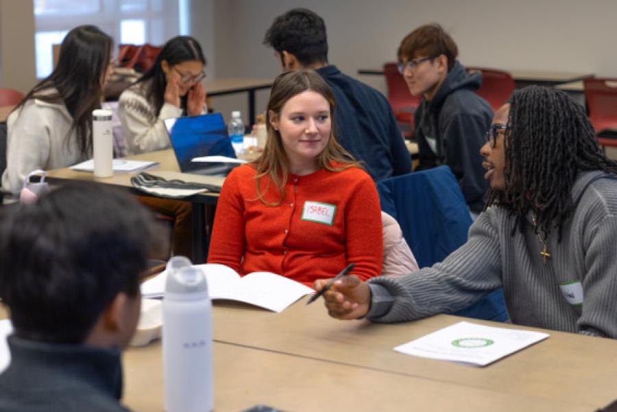 Students sit at tables, discussion together