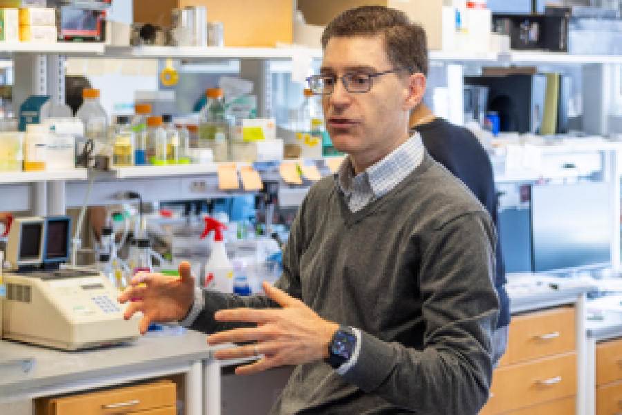 Person talking with lab equipment in the background