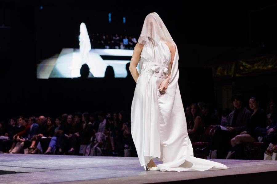 A person walking down a runway wearing a white dress