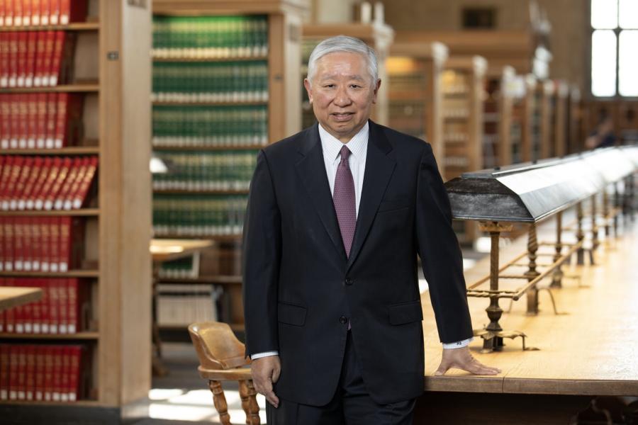 Person wearing a business suit stands in a law library with rows of book stacks behind him