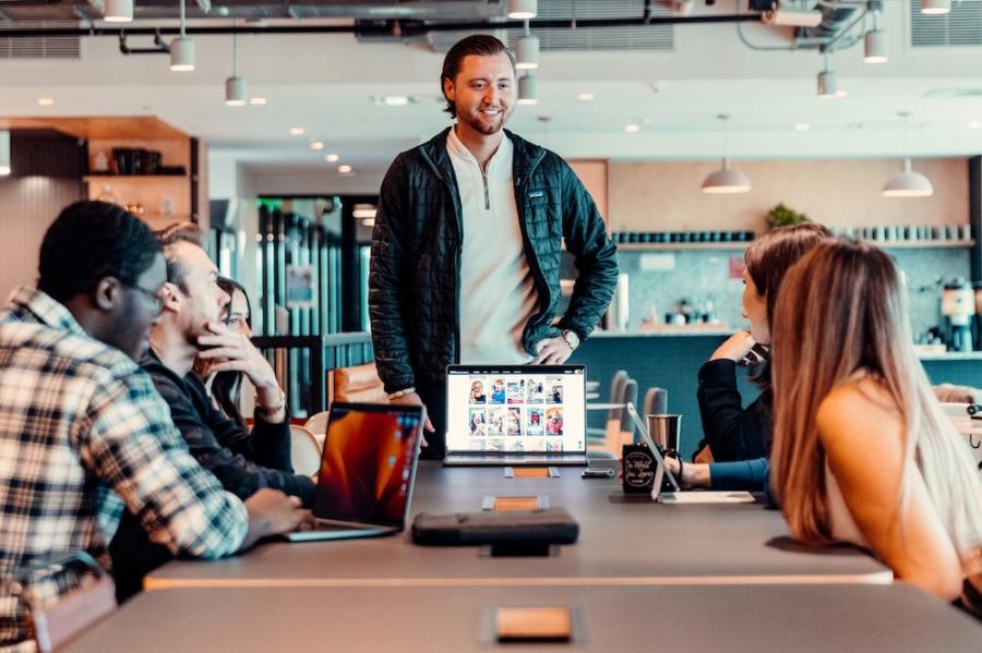 Person standing befor others, a computer open, looking confident