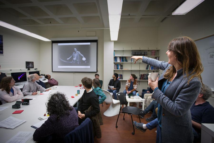 Professor Kaltenegger pointing at a screen showing a photo of Carl Sagan in a meeting.