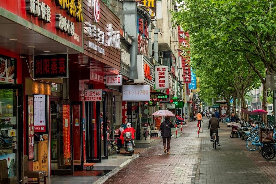 City street with people on a walkway and bright signs in Chinese lettering