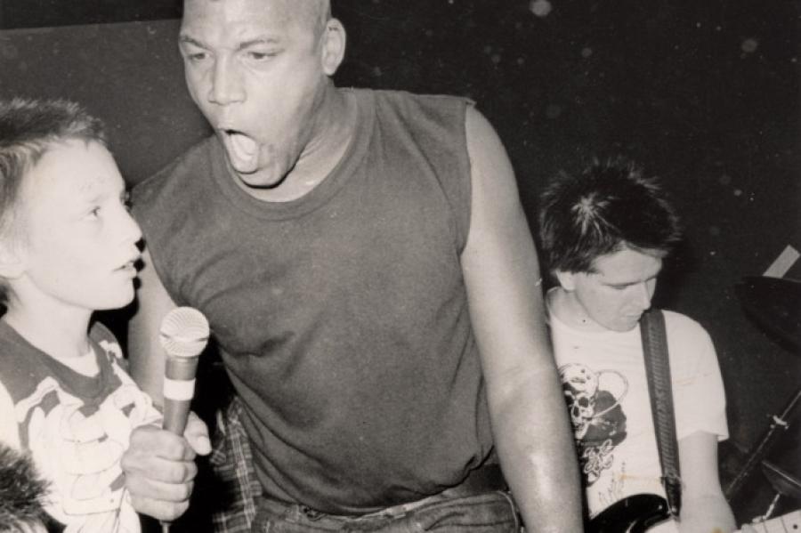 Black and white photo of a person hollering into a microphone with an intense look on his face