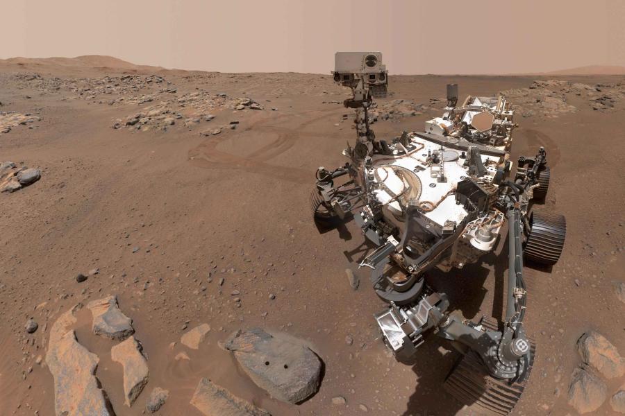 The Perseverance Rover looking at a Martian landscape of dry rocks and dirt.