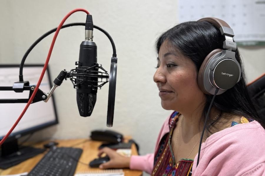 Person wearing large headphones, speaking into a microphone