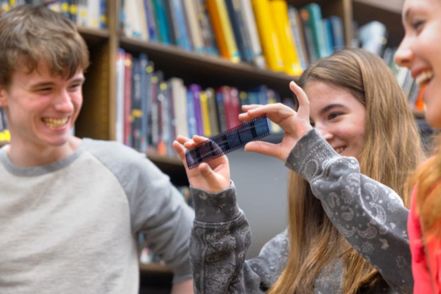 High school students smiling and looking at an old photo negative.