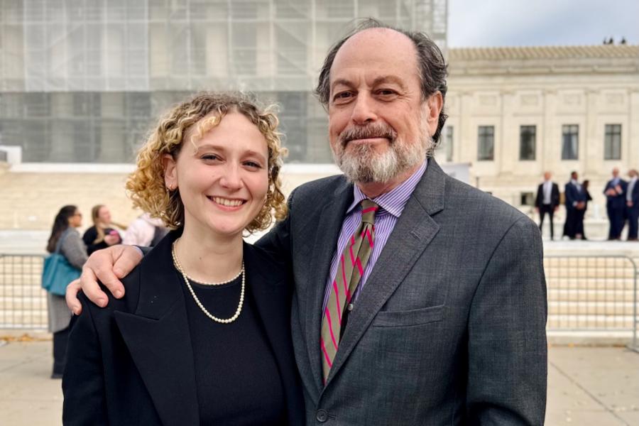 Two people dressed very well stand together in front of a large building