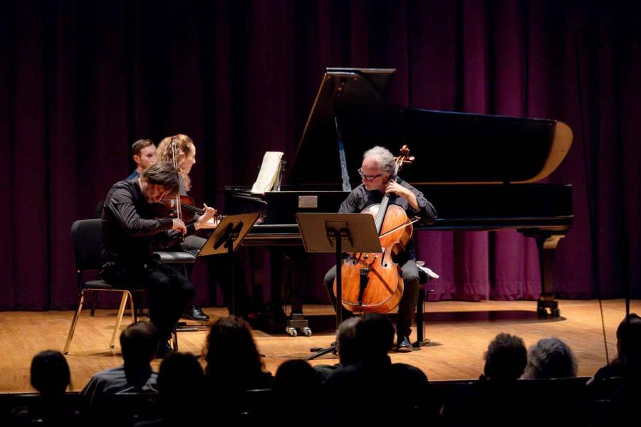 three people playing instruments on stage