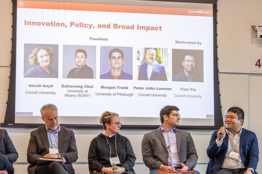 Five people on a stage with a screen behind them